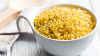A cup of bulgur wheat on a wooden table