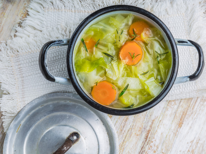 Cabbage soup with slices of carrot in a saucepan