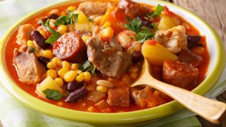 Cachupa, a slow cooked stew of corn, beans, vegetables and meat, popular in Africa in a green bowl