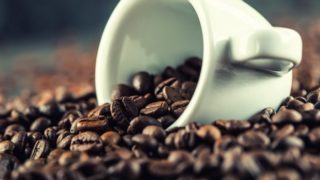 Extreme close-up of coffee beans with a small white cup