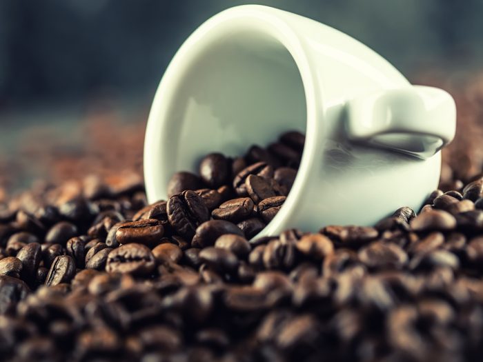 Extreme close-up of coffee beans with a small white cup
