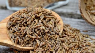 Close up of caraway seeds on a wooden spoon
