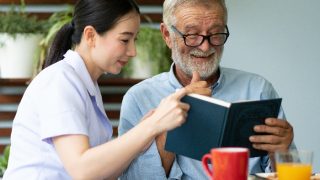 Young nurse taking care of a senior man at home