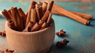Cinnamon sticks in a bowl and star anise on a blue background