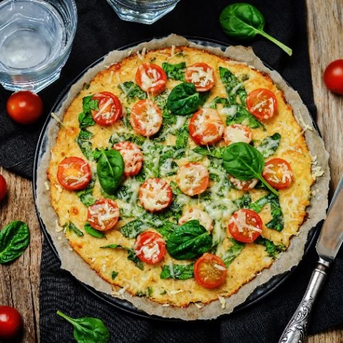 Cauliflower pizza crust with tomato and spinach