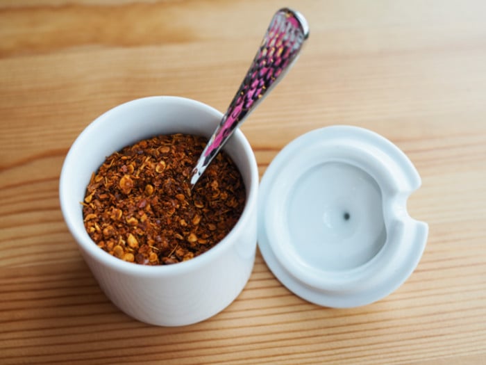 Small jar of cayenne pepper with a spoon in it.