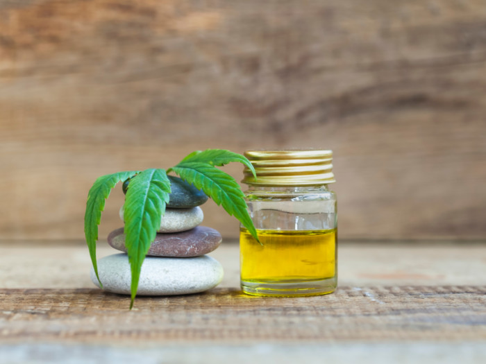 CBD oil bottle next to smooth stones and marijuana leaf
