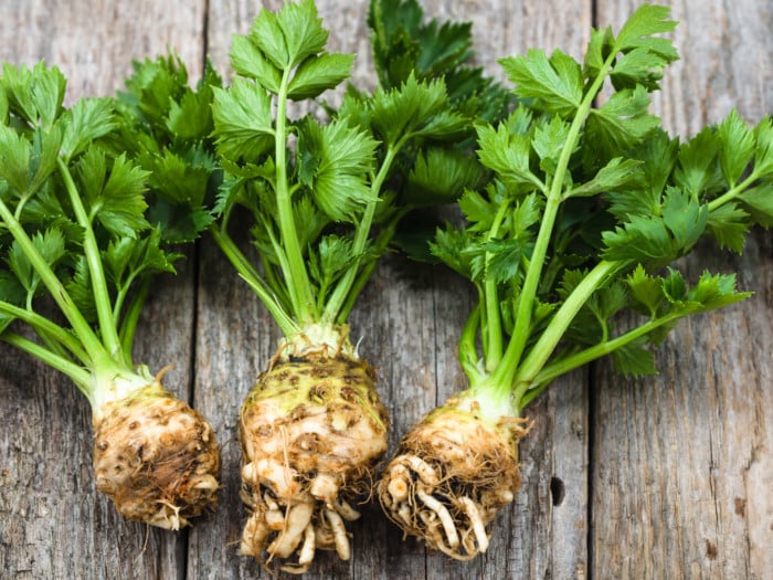 A close-up view of celery roots with leaves placed on a wooden table