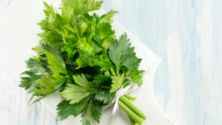 Whole celery on a white cutting board on a blue table