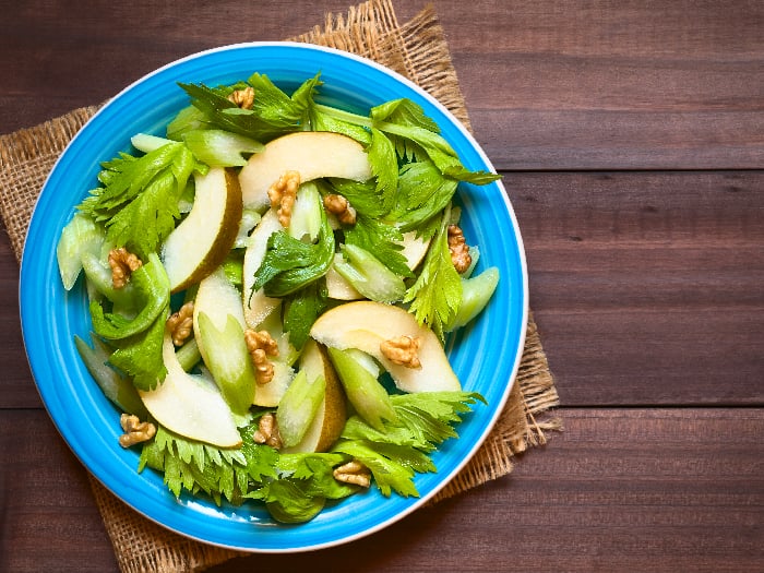 Fresh celery, pear, and walnut salad on blue plate