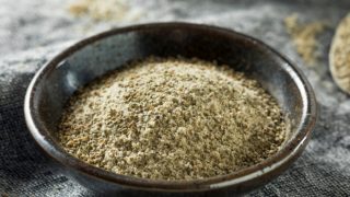 Celery salt in a flat black ingredient dish on a grey placemat