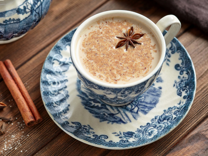 Cup and saucer of milky tea topped with star anise.