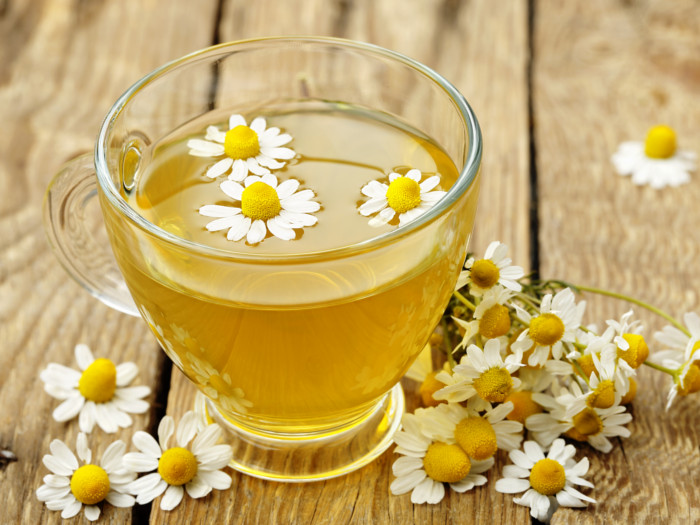 Chamomile tea in a glass cup with fresh chamomile flowers