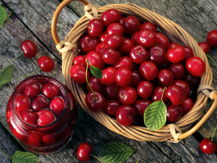 A basket of fresh cherries and a bottle filled with soaked cherries