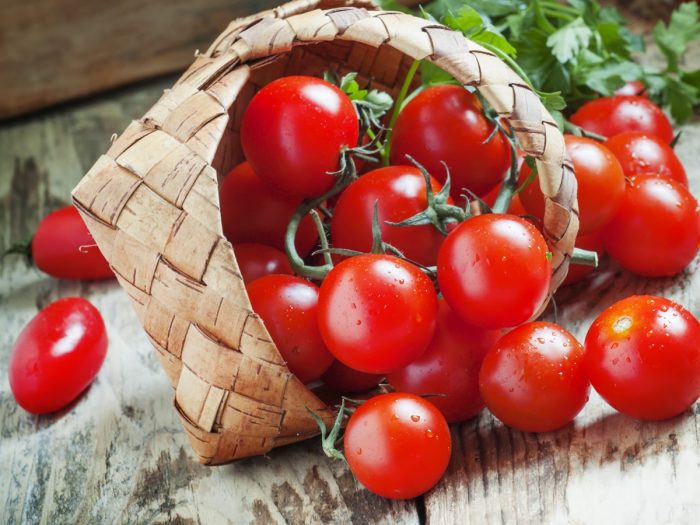 Cherry tomatoes spilling out of a wicker basket