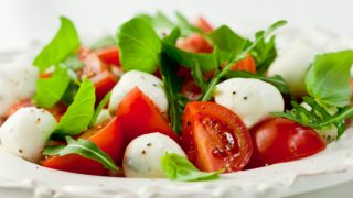 A plate of tomato salad with cheese and herbs