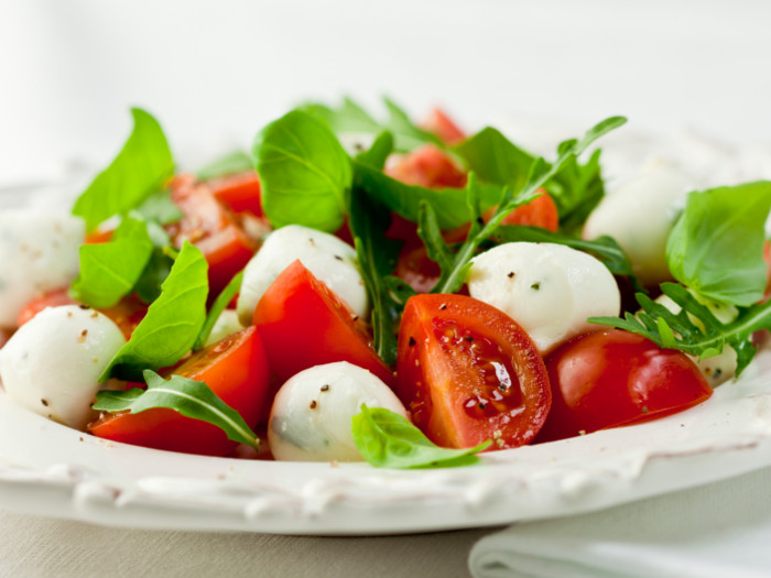 A plate of tomato salad with cheese and herbs