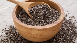 A bowl of chia seeds on a plain background