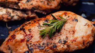 Grilled chicken breast fillets with rosemary on a dark background
