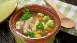 a casserole with chicken soup on a counter with a napkin and a wooden spoon