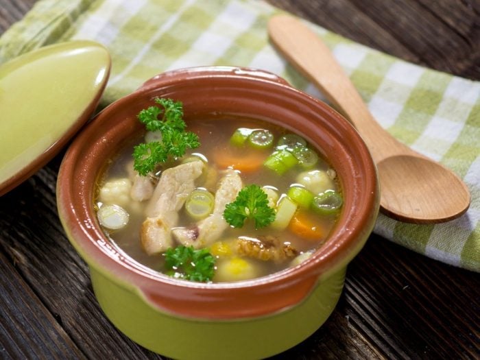 a casserole with chicken soup on a counter with a napkin and a wooden spoon