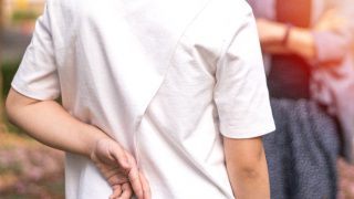 A child crossing fingers behind their back while facing an adult