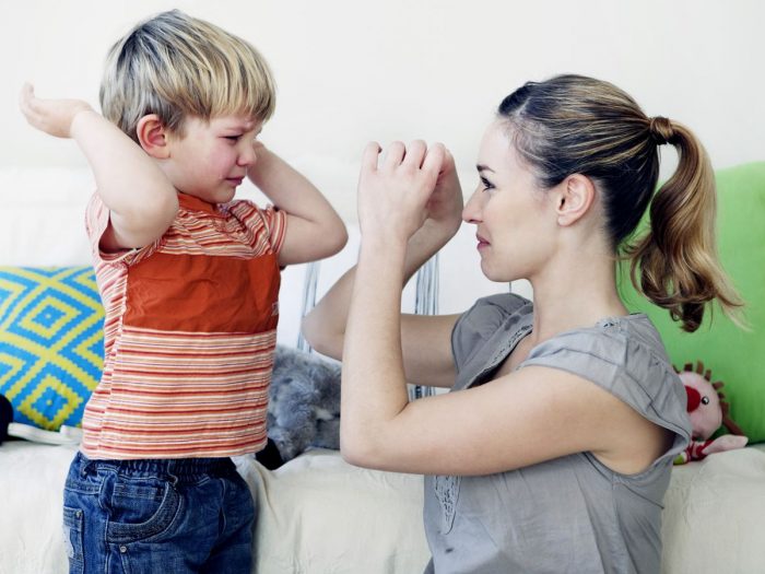 A child with hands half-raised about to cry while being distracted by an adult