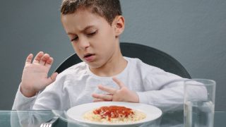 Child scared to eat food and pushing the plate away