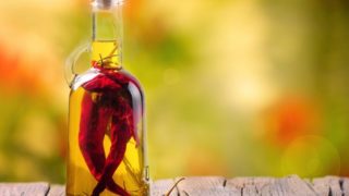 Close up of a chili oil bottle, infused with whole chilis and black pepper