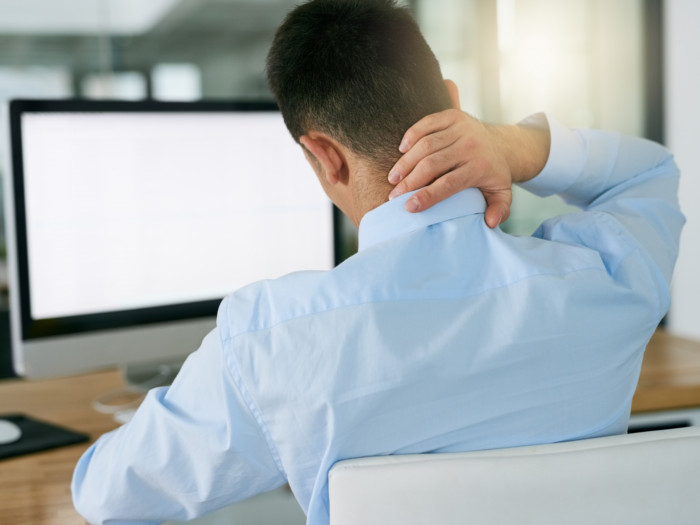 An employee holding the back of his neck due to pain caused by stress
