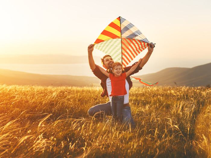 A father and son flying a kite outdoors, looking happy and relaxed