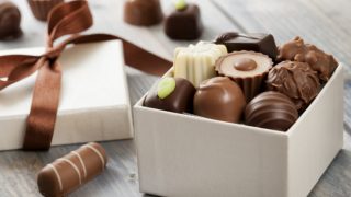 Assorted chocolates in a white gift box with a satin ribbon