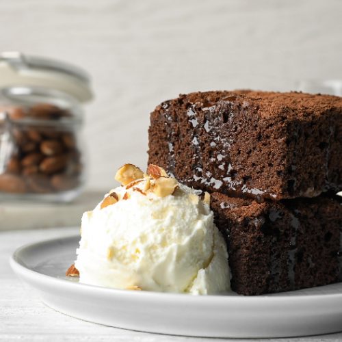 Plate with fresh brownies and ice-cream on table. Delicious chocolate pie