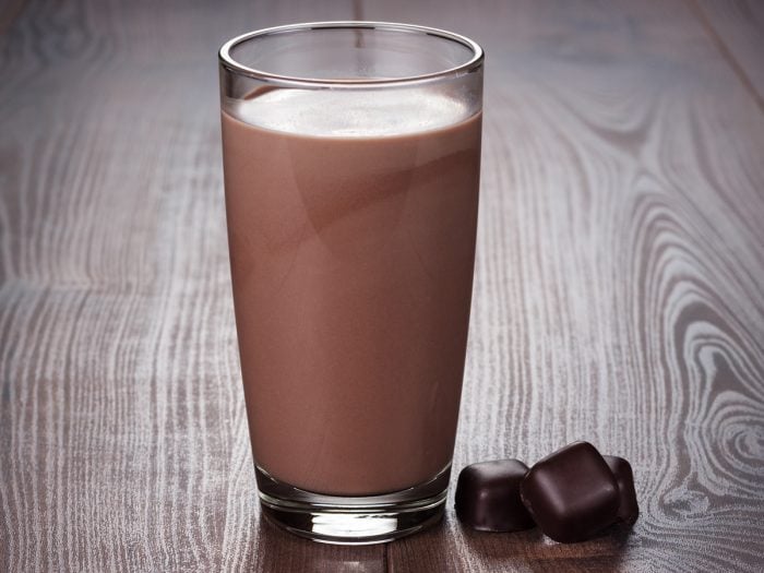 A glass of chocolate milk kept atop a wooden table