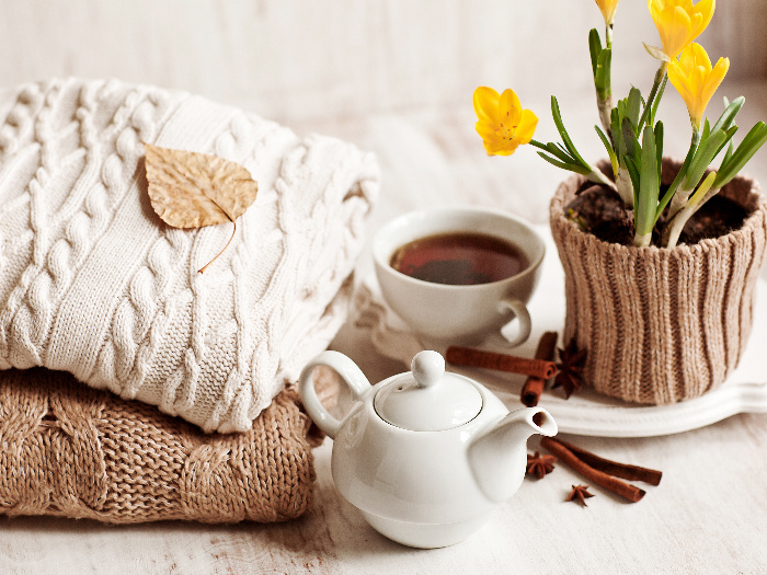 Cup of hot drink, knitting clothes, cinnamon and flowers