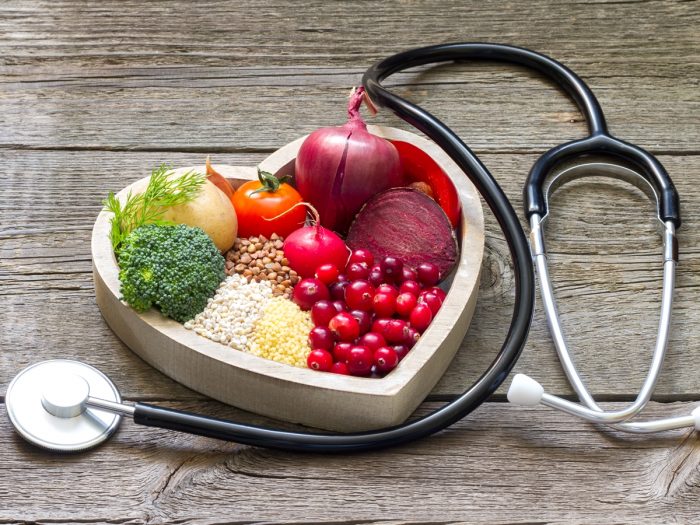 A heart shape plate of cholesterol diet (beet, legumes, broccoli, tomato, radish, beet, onion etc.) with a stethoscope