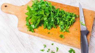 Chopped parsley on a wooden cutting board next to a knife