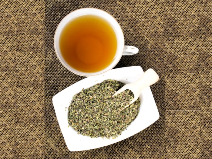 A cup filled with tea and loose leaf tea in a white bowl