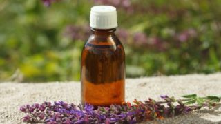 A bottle of clary sage oil with clary sage flowers