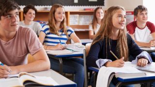 Teen students listening to the teacher in a classroom