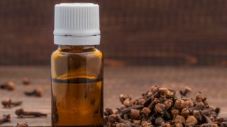 A clove oil bottle and a couple of cloves on a table