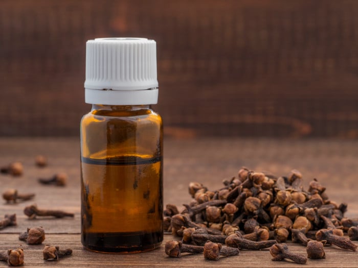 A clove oil bottle and a couple of cloves on a table