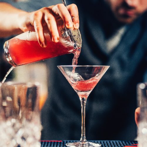 Barman pouring cocktail into a martini glass