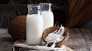 Glass bottles of coconut milk, whole coconut, and shelled coconut meat