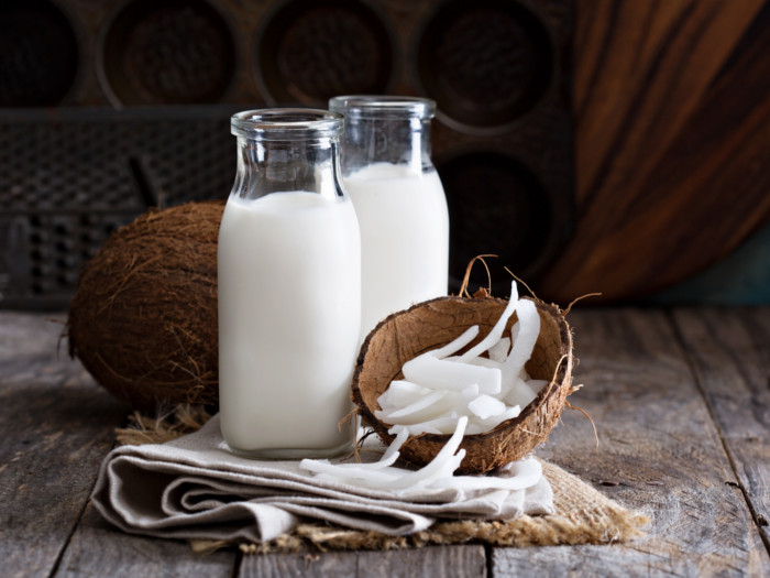 Glass bottles of coconut milk, whole coconut, and shelled coconut meat