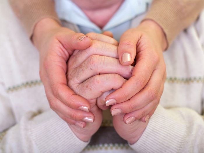 Hands reassuring and holding a senior person's hands