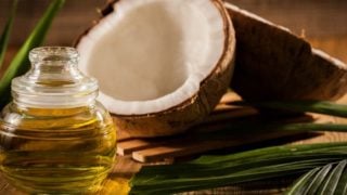 Coconut, leaves, and coconut oil on a wooden table