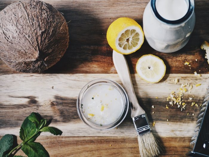 Coconut cream, sliced lemon, lemon rind, and whole coconut on wood