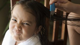 A mother combing a little girl's oiled hair to remove lice