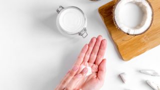 Coconut oil and half coconut on a wooden cutting board